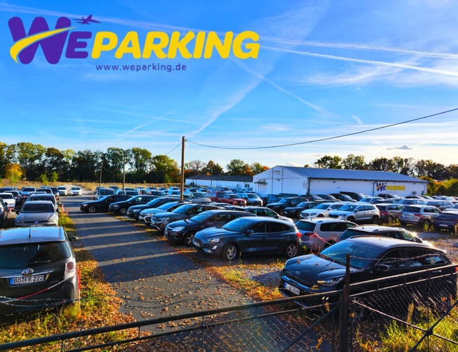 Duży otwarty parking WE Parking z wieloma zaparkowanymi samochodami w słoneczną pogodę.