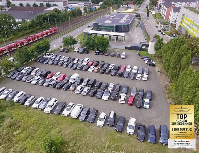 Parking Mein-Flughafenparkplatz-Frankfurt P1. Zdjęcie z lotu ptaka na duży parking z wieloma zaparkowanymi samochodami i budynkami w tle.