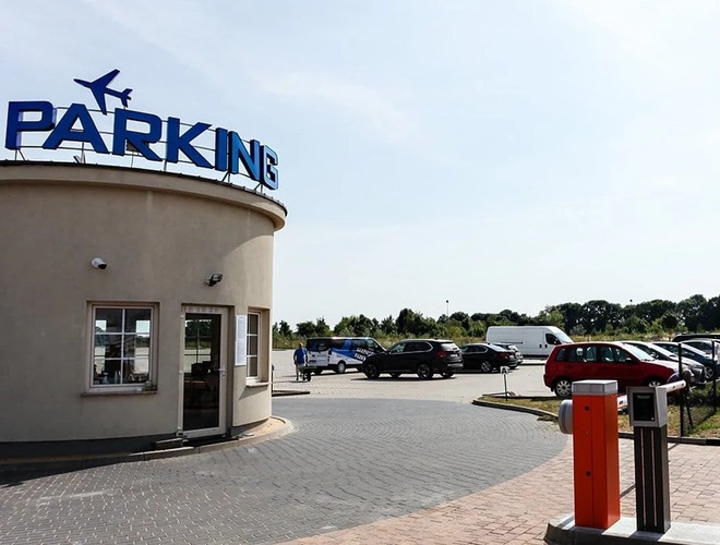 Widok biura parkingu, terenu parkingu w pełni wyłożonego kostką brukową.