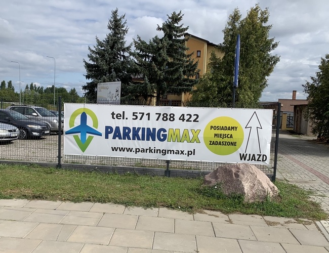 A1 Parking Max – Parkovisko je ohradené sieťou. Na území stoja zaparkované autá. Je viditeľný veľký billboard s reklamou.