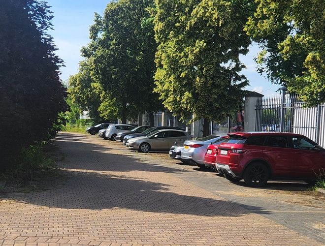 Belvárosi, olcsó és biztonságos SMART parkolóhely - Az autók az árok mentén állnak. A terület térkővel burkolt és fákkal körülvett.
