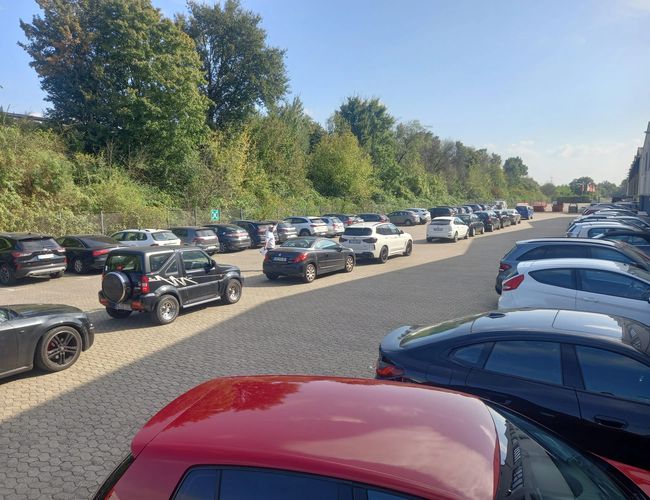 Parking Elite Parken Köln - Parking jest pełen samochodów. W tle rosną drzewa. Nawierzchnia parkingu jest z kostki brukowej.
