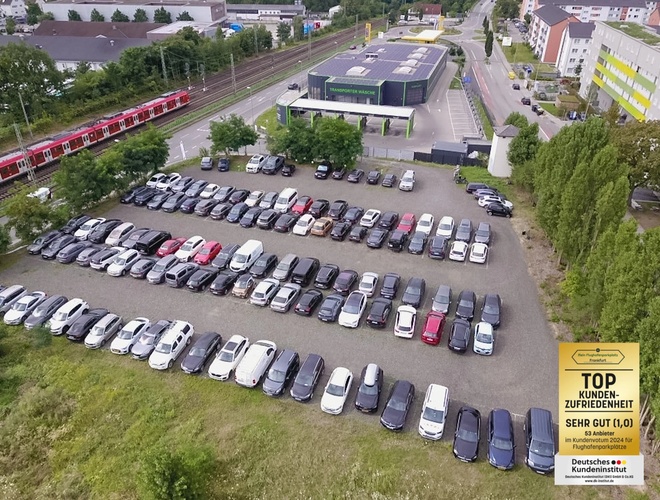 Parkplatz Mein-Flughafenparkplatz-Frankfurt P1. Luftaufnahme eines großen Parkplatzes mit vielen geparkten Autos und Gebäuden im Hintergrund.