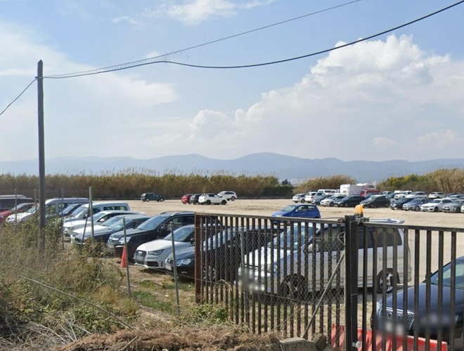 Central Parking Valet – Parking jest ogrodzony i pełen samochodów. Na terenie widoczne są zaparkowane auta. Czyste niebo w tle.