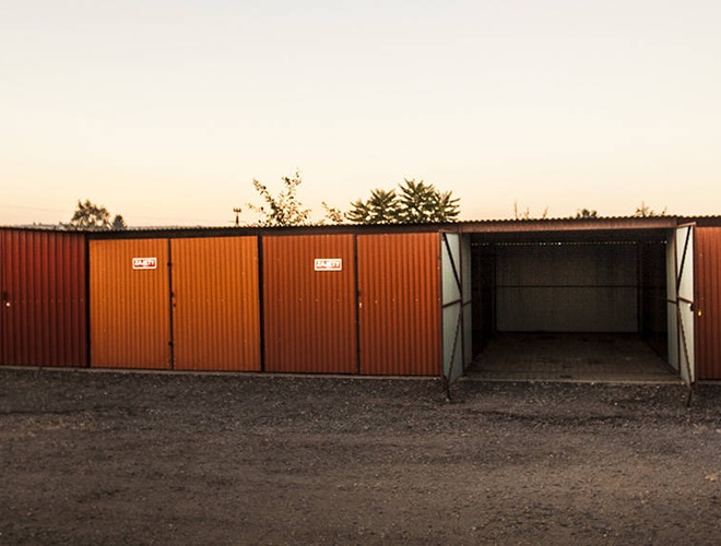 PERI Parking Garajes Premium — fila de garajes metálicos. Sin cercado visible. El terreno parece espacioso y de grava.