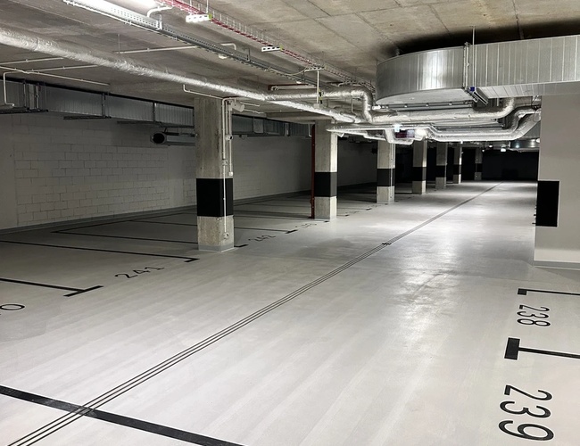 Najvyššia parkovacia garáž - Podzemné, moderné parkovisko s vyznačenými miestami. Svetlo a ventilácia sú viditeľné na strope. Priestor je jasný a čistý.