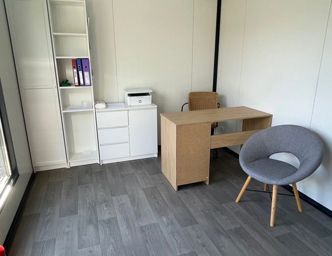 Parking Simple Park – wnętrze poczekalni z drewnianymi ścianami. Sofa i fotel w rogach. Na komodzie stoją napoje i czajnik.