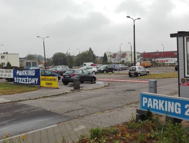 Parking JM Auto - Parking jest strzeżony i oświetlony. Widać kilka zaparkowanych samochodów.