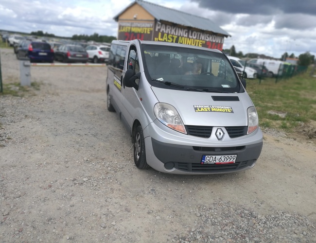 Parking P8 - Na parkingu stoi srebrny van. Teren jest żwirowy i ogrodzony. W tle są zaparkowane samochody.