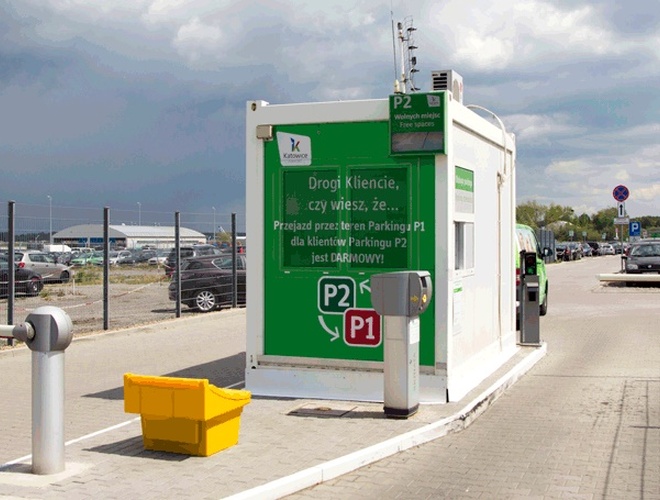Aparcamiento Oficial P2 - Cabina con un gran cartel en la entrada. Las barreras y la cerca son visibles al fondo.