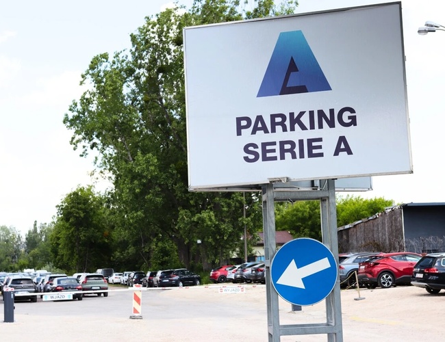 Najlepšia parkovacia séria A - Veľky znak pri vstupe. Početné zaparkované autá okolo. Areál obklopený zeleňou.