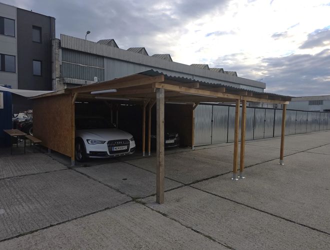 Zadaszone miejsca parkingowe PV Airport Parking w Bratysławie – samochody zaparkowane pod drewnianą wiatą na utwardzonym terenie parkingu