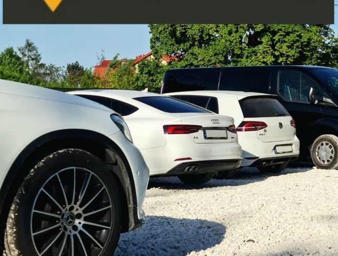 MyParking – Na żwirowym parkingu stoją samochody. Teren otoczony jest zielenią.
