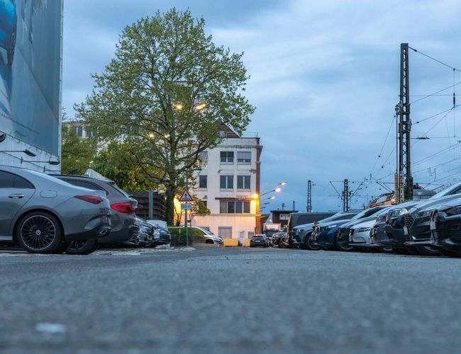 Parking Clean Valet Parkservice – Samochody stoją blisko siebie. Po lewej stronie widać billboard, po prawej latarnie.