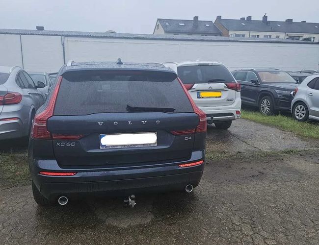Parking Weltparking – Na parkingu stoi kilka samochodów. Teren jest nieutwardzony i otwarty. W tle widoczne są budynki.