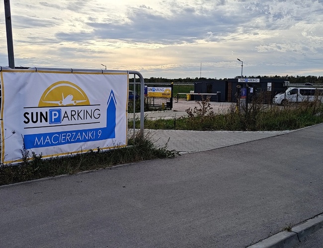 Parkovisko Sun – Na nádvorí stoja vozidlá. Vidno plot a bannér. Pozemok je spevnený a osvetlený.