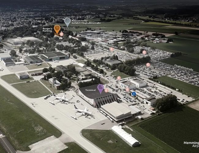 Widok lotniczy na kompleks budynków z rozległymi parkingami oraz drogami wewnętrznymi.