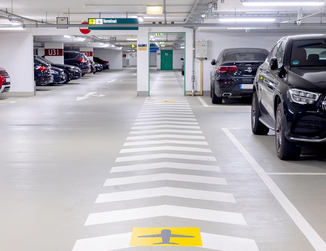 Wnętrze parkingu P8 z oznakowanymi miejscami postojowymi, szerokimi alejkami oraz zaparkowanymi samochodami.