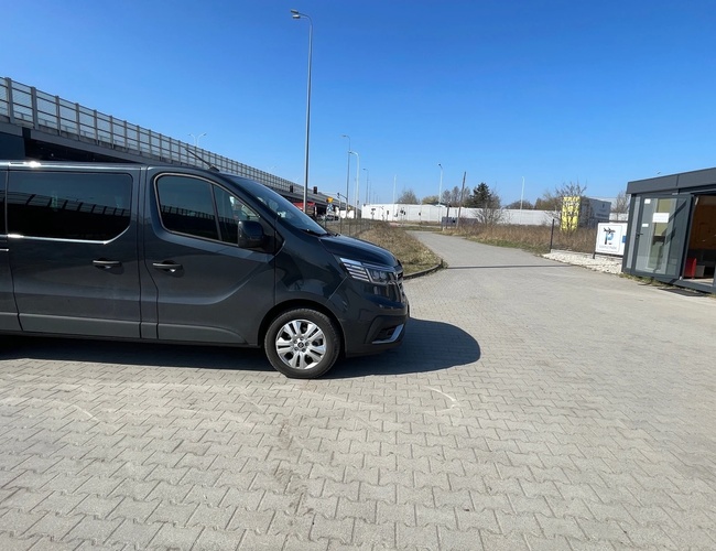 Parkovanie Simple Park – vedľa kancelárie stojí čierne dodávka. Zakrýva modrú oblohu. Pozemok je otvorený a spevnený.