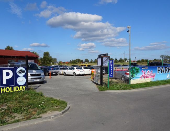 Ferieparkering Gdańsk - Parkeringen er inngjerdet og opplyst. Det er ulike personbiler parkert. Området er romslig og velstelt.