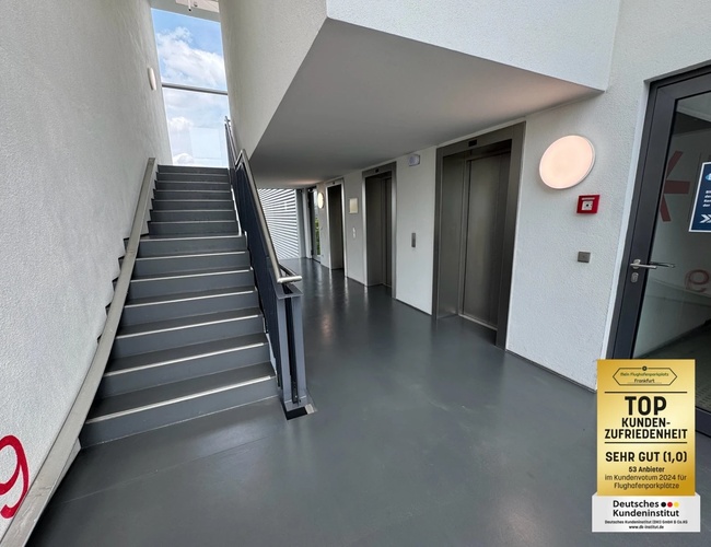 Parkovisko Mein - Letisko Frankfurt ShortWay - Viššpodlažné parkovisko je prázdne. Kovové zábradlia bežia pozdĺž strán. Je osvetlené zářivkami.