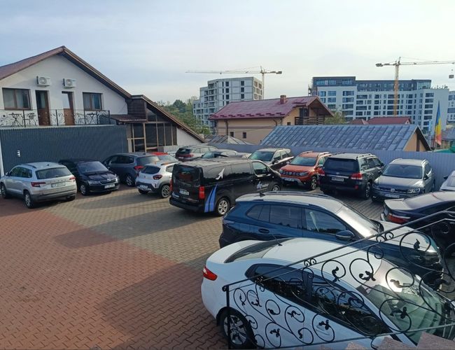 Teren parkingu Sky Park przy lotnisku w Iași – przestrzeń parkingowa z zaparkowanymi samochodami osobowymi oraz budynkiem znajdującym się przy parkingu.