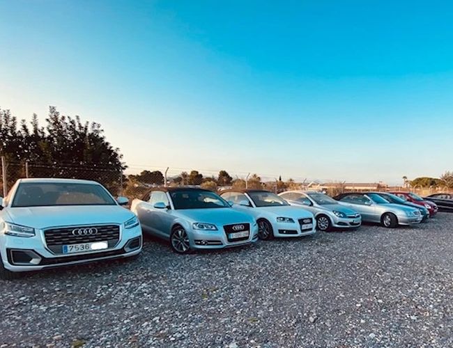 The Best Parking Alicante Outdoor Valet – Rząd zaparkowanych samochodów na żwirowym terenie. Parking jest otoczony ogrodzeniem.