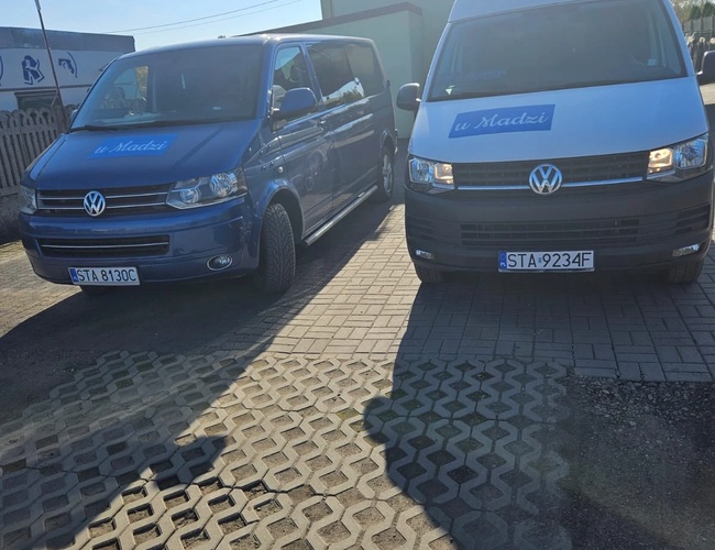 Aparcamiento U Madzi – Dos vehículos están estacionados en una superficie pavimentada. Los vehículos están marcados con el logotipo. Al fondo se puede ver un edificio.