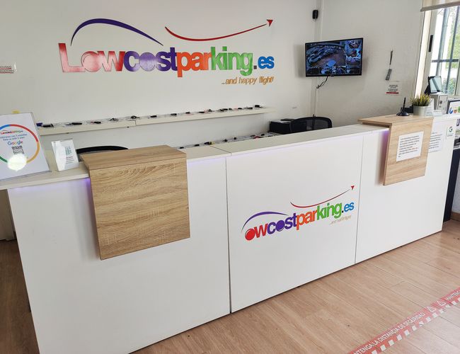 Lowcost Parking Walencja – Biurko recepcyjne z logo firmy. Na ścianie wisi monitor z obrazem z kamer.