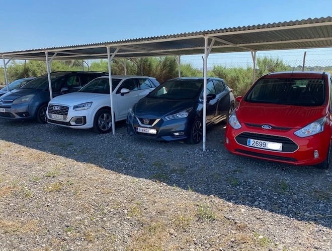 El mejor aparcamiento cubierto de Alicante con servicio de valet - Los coches están bajo techo. El aparcamiento está cercado y es de grava. Hay arbustos creciendo a los lados.