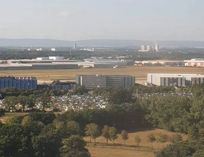 Panorama lotniska przedstawiająca terminale, parkingi oraz infrastrukturę komunikacyjną, ukazująca rozległy obszar portu lotniczego z lotu ptaka.