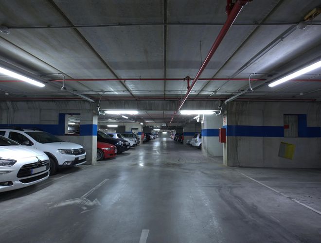 Oliveral parkoló - Az alagsorban parkoló autók állnak. A terület jó világítású. Középen egy mozgásterület található.