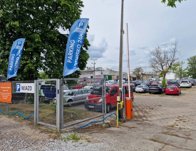 Widok wjazdu na parking i ogrodzenie.