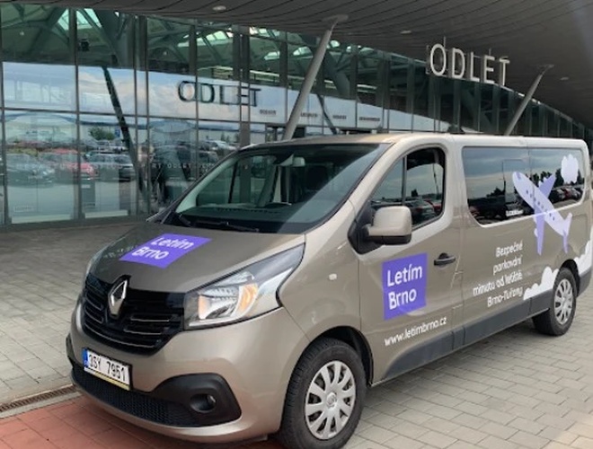 Parking Letim Brno II – kilka samochodów stoi na żwirowanym placu. Teren jest otwarty i nasłoneczniony. W tle rosną drzewa.