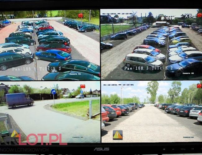 Aparcamiento P38 – Hay coches aparcados en la plaza. El área está cercada y monitoreada por cámaras. En el fondo se pueden ver árboles.