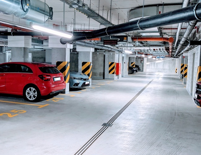 Odlet Garage - Vo vnútri podzemného parkoviska stoja zaparkované automobily. Miesta sú označené číslami. Areál je dobre osvetlený.