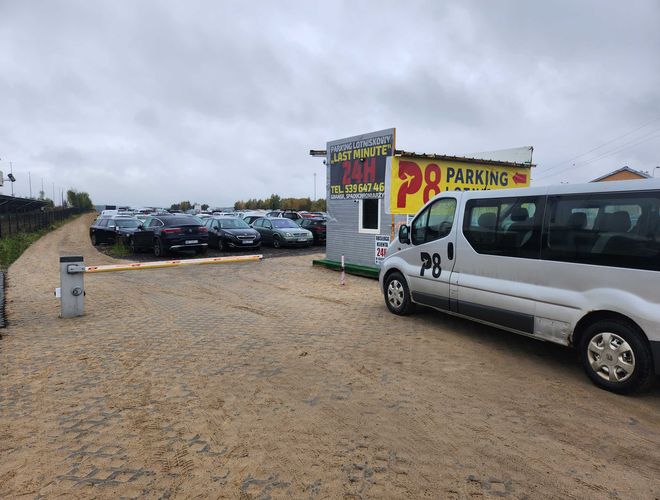 Parking P8 - Plac jest utwardzony i ogrodzony. Widać wiele zaparkowanych aut. Na zdjęciu jest też bus z logo parkingu.
