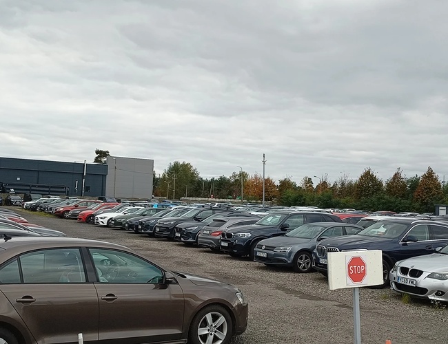Parking ArtLot - En el aparcamiento hay muchos coches. El terreno está abierto y sin cercar. El tiempo está nublado.