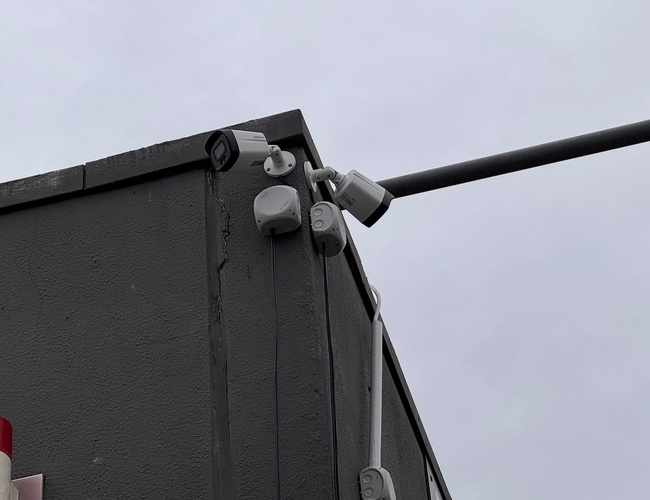 Prime Parking Valet – na stene budovy sú namontované kamery. Prístroj je zameraný smerom von. Vedľa je viditeľný vyčnievajúci prvok.