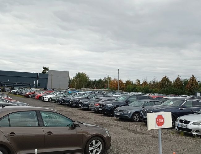 Parking ArtLot - En el aparcamiento hay muchos coches. El terreno está abierto y sin cercar. El tiempo está nublado.