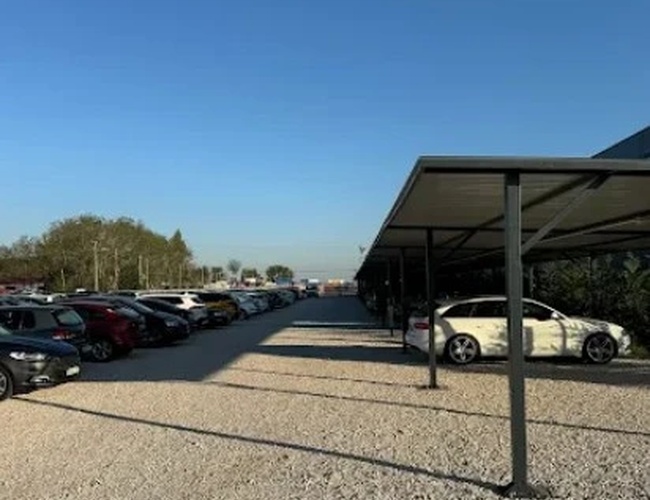 Przestronny plac parkingowy z nowoczesnymi wiatami chroniącymi samochody przed warunkami atmosferycznymi