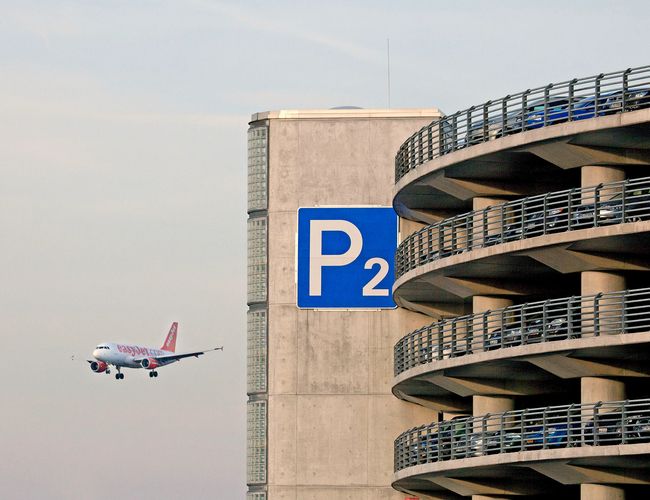 Parking P2 z charakterystyczną wielopoziomową konstrukcją, widoczny podczas lądowania samolotu w pobliżu lotniska.