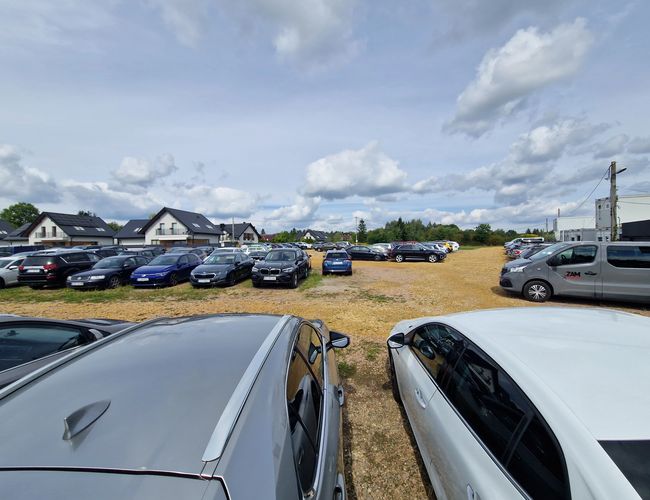 Plac parkingowy z utwardzoną nawierzchnią i zaparkowanymi samochodami