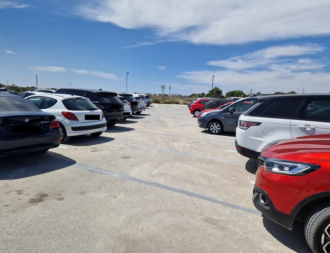 Monster Parking – Na otvorenom dvore stoja zaparkované osobné vozidlá. Obloha je čiastočne zamračená. Parkovisko je priestranné a osvetlené.