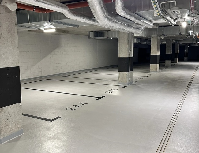 Nádvorie Supreme Parking – Podzemná garáž s číslovanými miestami. Viditeľné osvetlenie a stropné inštalácie.