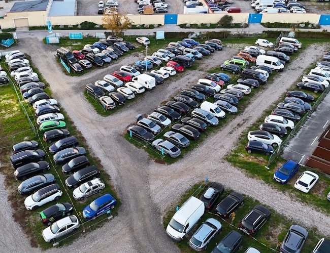 Parqueo de Aeropuerto Parktiger 2 - El estacionamiento tiene una superficie de grava. Los coches están alineados en filas ordenadas. El área está cercada y bien iluminada.