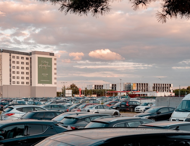 Parking Strachowice - Na zdjęciu widoczny jest zatłoczony parking samochodowy. W tle znajduje się budynek hotelu.