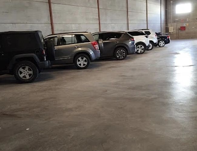 Premium Parking VLC – Wnętrze zadaszonego parkingu z samochodami. Ściany są betonowe, a powierzchnia jest szeroka. W tle widać światła.