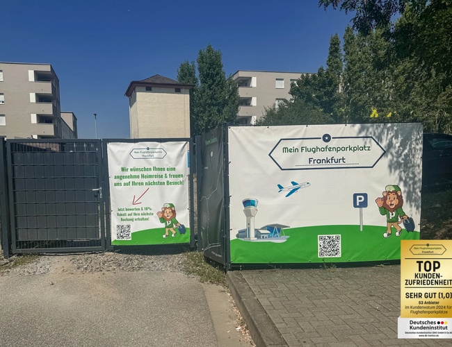 Parking Mein-Flughafenparkplatz-Frankfurt P1. Brama wjazdowa na teren parkingu z banerami reklamowymi i budynkami w tle.