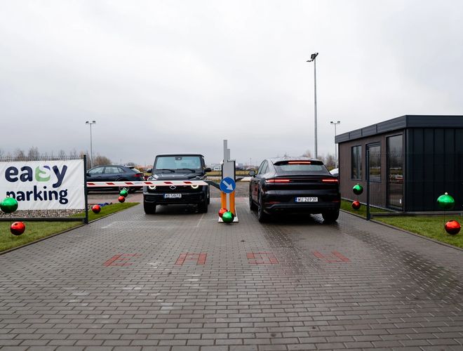 Easy Parking Standard - two barriers at the entrance to the parking lot with two cars, one at the exit and one at the entrance, banner on the fence with the name of the parking lot